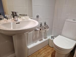 a white bathroom with a sink and a toilet at Landing Cottage Guest House in Newby Bridge