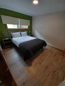 1 dormitorio con cama y pared verde en APART HOTEL SUVERAL, en Puerto Montt