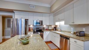 a large kitchen with white cabinets and a refrigerator at 201 York #3 · Homey Downtown 2 Bedroom Steps from the River in Savannah