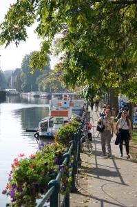 personas caminando por una acera junto a un río con un barco en Artist's Loft & Garden, en Gante