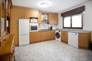 a kitchen with wooden cabinets and a white refrigerator at Vega La Escuela megustarural in Llanes