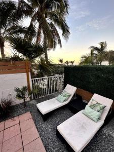 2 Stühle und eine Bank auf einer Terrasse mit Palmen in der Unterkunft The Mini Coconut in Marathon