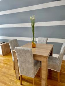 a wooden table with chairs and a vase with flowers at Naki apartman in Podgorica