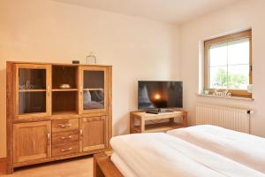 a bedroom with a large wooden cabinet and a television at Ferienwohnung Schatz in Breitenwang