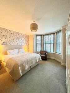 a bedroom with a bed and a chair and windows at Mode Apartments St Annes in Lytham St Annes