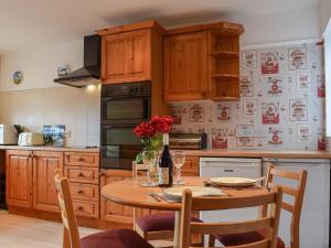 a kitchen with a wooden table with red flowers on it at Glossoms Lodge in Scalford