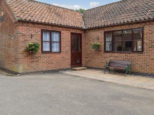 a brick house with a bench in front of it at Glossoms Lodge in Scalford