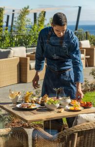 a man in an apron preparing food on a table at Les Suites at The Cliff Bay - PortoBay in Funchal