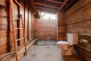 a bathroom with a toilet and a wooden wall at Moson Villa Legian in Seminyak