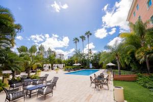a patio with chairs and a pool and palm trees at Hodelpa Garden Court in Santiago de los Caballeros