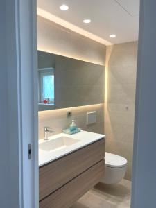 een badkamer met een wastafel, een toilet en een spiegel bij Modern 3 bedroom apartment situated in luxury beachfront gated community in Torremolinos