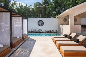 an outdoor patio with chairs and a swimming pool at Illa Cozumel in Cozumel