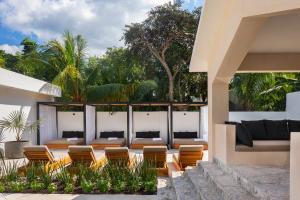 a patio of a house with chairs and a couch at Illa Cozumel in Cozumel