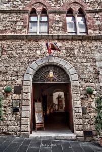 a brick building with an archway with a flag at Residenza d'Epoca Palazzo Malfatti in Massa Marittima