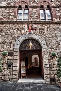 ein Backsteingebäude mit einem Torbogen mit einer Flagge in der Unterkunft Residenza d'Epoca Palazzo Malfatti in Massa Marittima