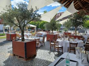 a restaurant with tables and chairs with a tree in a planter at Hotel Gutshof Herborn in Herborn