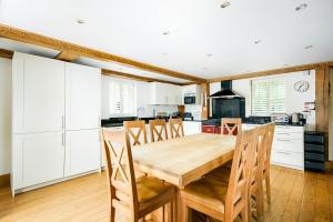 a kitchen with a wooden table and white cabinets at Lakeside property with hot tub Barn Owl HM08 in Somerford Keynes
