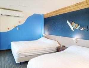 Cette chambre comprend 2 lits et une fresque murale représentant des roquettes. dans l'établissement Breeze and Waves Hostel, à Jinning