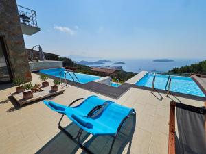einem blauen Stuhl auf einer Terrasse neben einem Pool in der Unterkunft Sky Sea Resort Skiathos in Skiathos-Stadt