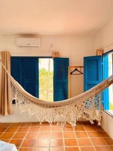 eine Hängematte in einem Zimmer mit blauen Fenstern in der Unterkunft Montepascual Ecovillage in Lagoinha