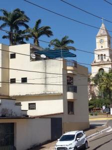 a white car parked in front of a building with a clock tower at Canastra Season in São Roque de Minas