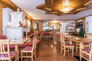 un restaurante con mesas y sillas de madera y una lámpara de araña en Residence Park Imperator Bilocale 1, en Carisolo