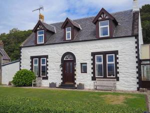 una casa blanca con techo negro y banco en Dunmaghlas en Pirnmill