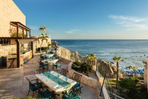 an outdoor patio with tables and chairs and the ocean at Hacienda Resort in Cabo San Lucas