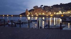 a city lit up at night with boats in the water at Appartamento e Mansarda al mare in Rio Marina