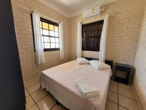 a bedroom with a white bed with two towels on it at Pousada Genoveva - Casa a beira mar in Laguna