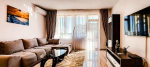 ein Wohnzimmer mit einem Sofa und einem TV in der Unterkunft Lighthouse Golf Resort, 75 mp2, with balcony in Baltschik