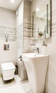 a white bathroom with a sink and a toilet at Lighthouse Golf Resort, 75 mp2, with balcony in Balchik