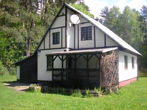 una pequeña casa en blanco y negro con un patio de césped en Domek Letniskowy - Jerutki en Jerutki