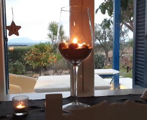 a glass of wine sitting on a table with a candle at Haus Asterakia in Aliko Beach