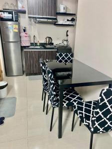 uma cozinha com uma mesa preta com cadeiras e um frigorífico em The persimmon condominium mabolo cebu city em Cebu