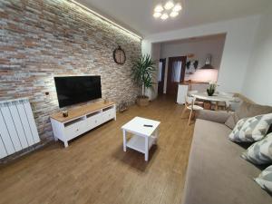 sala de estar con pared de ladrillo y TV de pantalla plana en Casa eNNe, Appartamento Vicino Centro e Juventus Stadium en Turín