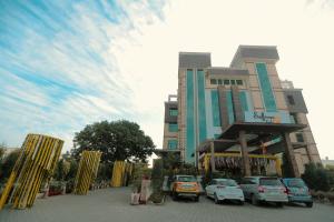 un bâtiment avec des voitures garées devant lui dans l'établissement Hotel Saffron Leaf, à Dehradun