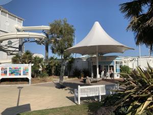 um parque com um banco branco e um guarda-chuva em Club Tropicana em Poole