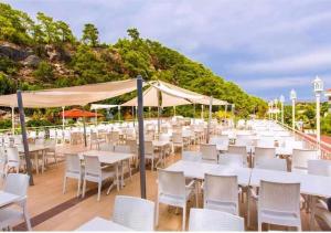 a row of tables and chairs with white tables and umbrellas at Golden Sunset Hotel&spa in Kemer