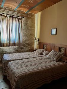 a bedroom with two beds and a window at Hostal meson del rey in Olocau del Rey