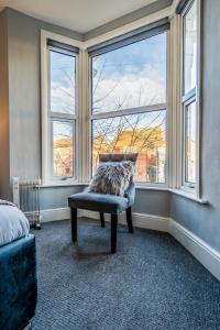 a bedroom with a chair in front of a window at Derby Road Suite in Kegworth