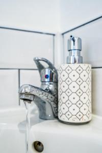 a bathroom sink with a faucet and a soap dispenser at Derby Road Suite in Kegworth