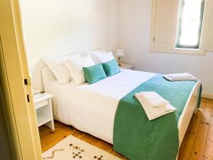 um quarto com uma grande cama branca com travesseiros azuis em Quintinha de Pinouco em Resende mais 37 fotografias