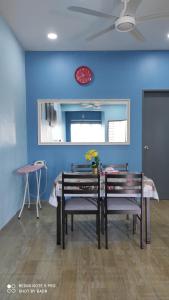 uma sala de jantar com uma mesa e um relógio vermelho numa parede azul em Ain's Homestay em Kangar