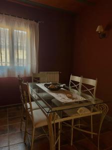 a dining room table and chairs with a glass table and a window at Hostal meson del rey in Olocau del Rey