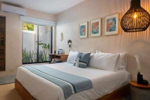 a bedroom with a large white bed and a window at Illa Cozumel in Cozumel