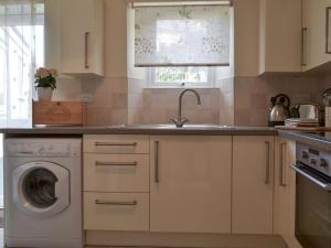 a kitchen with a sink and a washing machine at Bridgend Cottage in Lostwithiel