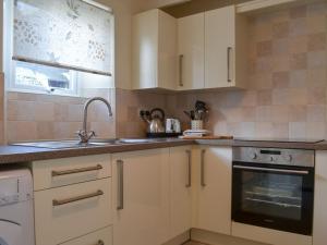 a kitchen with white cabinets and a sink at Bridgend Cottage in Lostwithiel