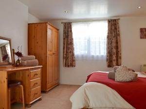 a bedroom with a bed and a dresser and a window at Bridgend Cottage in Lostwithiel