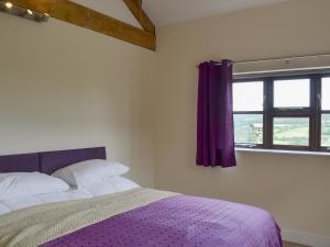 1 dormitorio con cama morada y ventana en The Barn - Ukc3750, en Charmouth